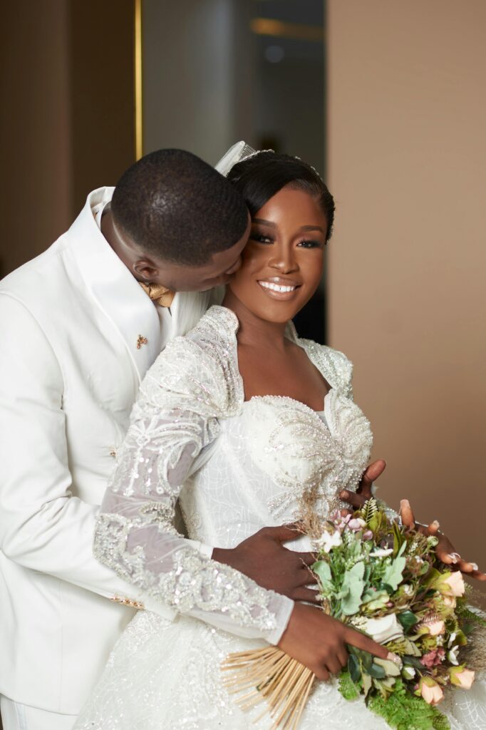 A happy newlywed couple sharing a tender moment in elegant attire indoors.