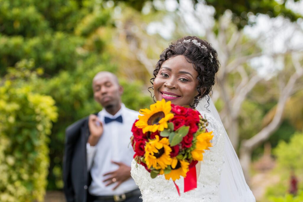 Joyful bride and groom celebrating their wedding with vibrant floral bouquet outdoors in Nampula.