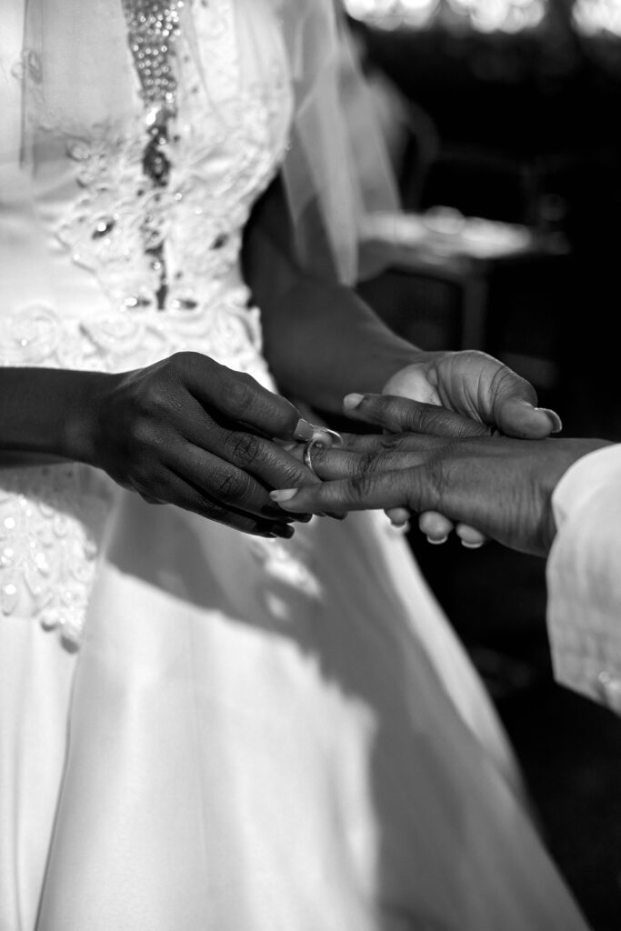 Elegant black and white close-up of a couple exchanging wedding rings during the ceremony.